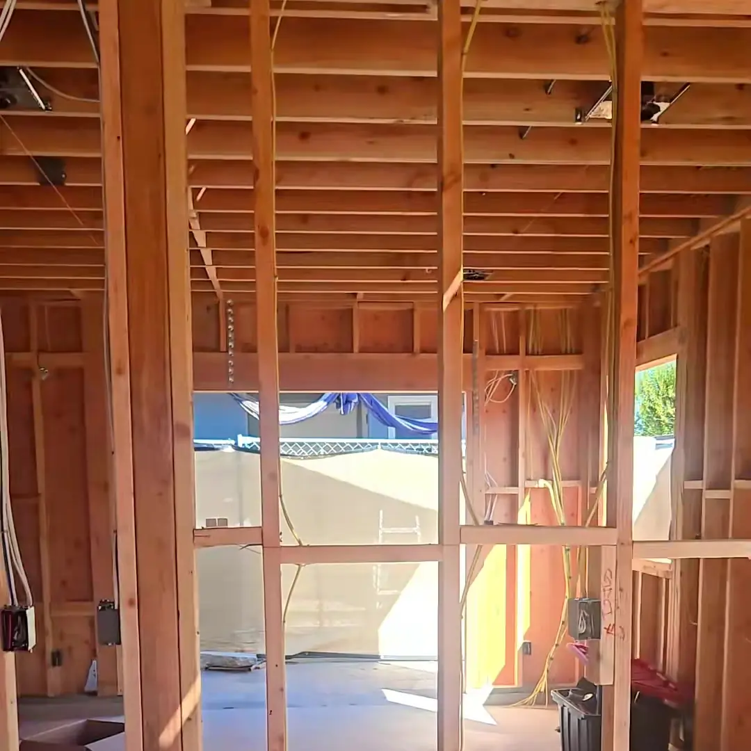 Inside a framed ADU: wood stud walls, roof joists and a window opening