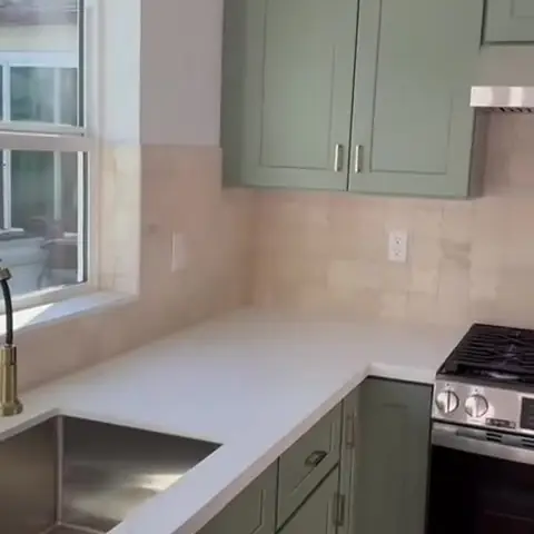 Finished kitchen with green shaker cabinets, quartz counters and a stainless range