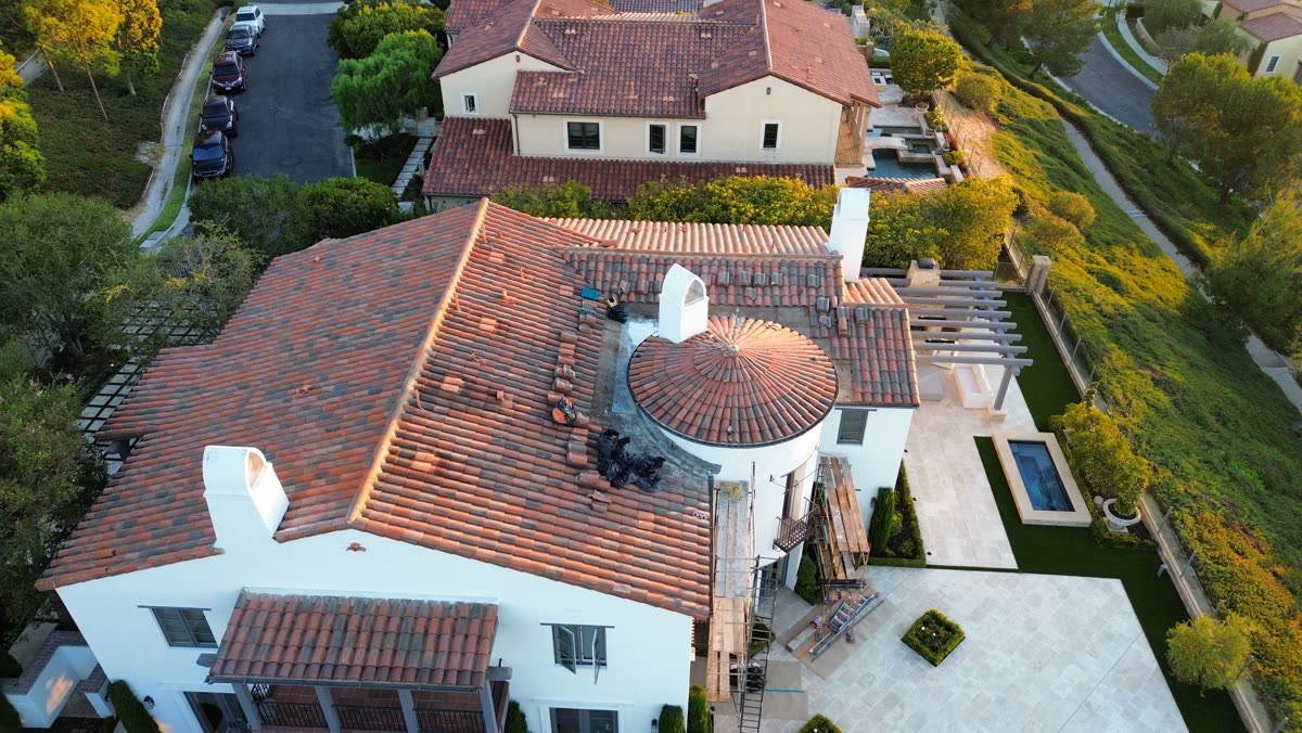 Aerial view of a hillside home with a finished clay tile roof