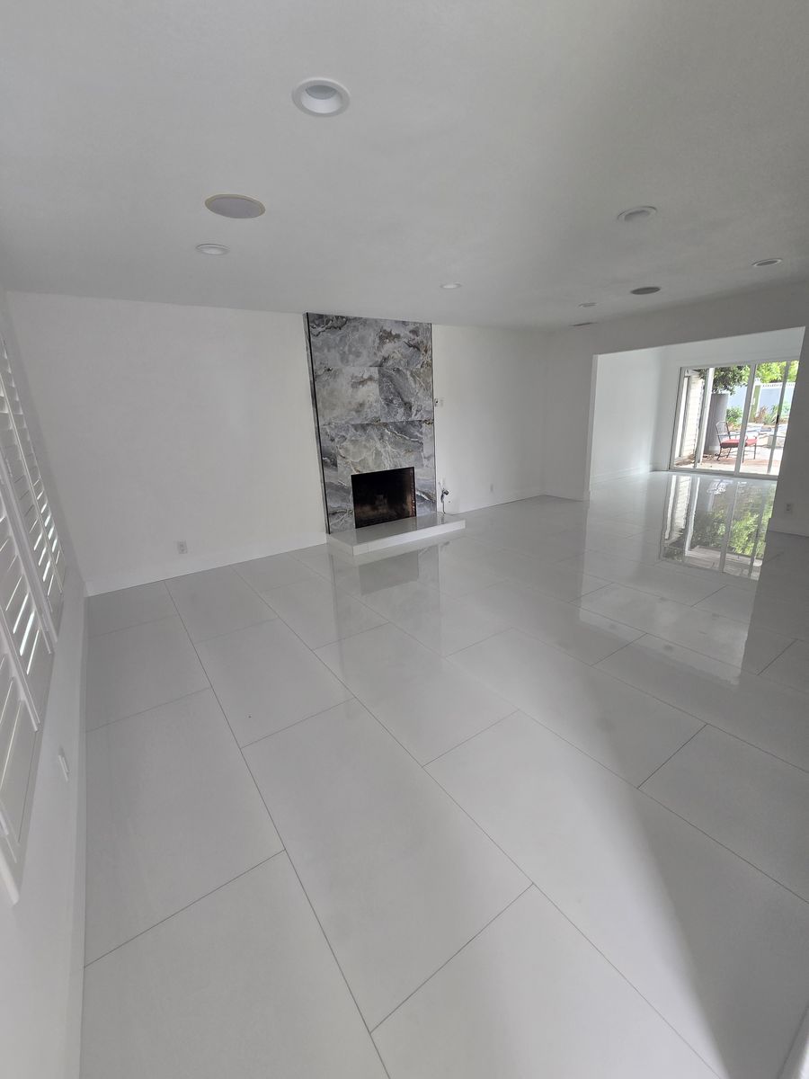 Remodeled living room with large white floor tile and a decorative fireplace