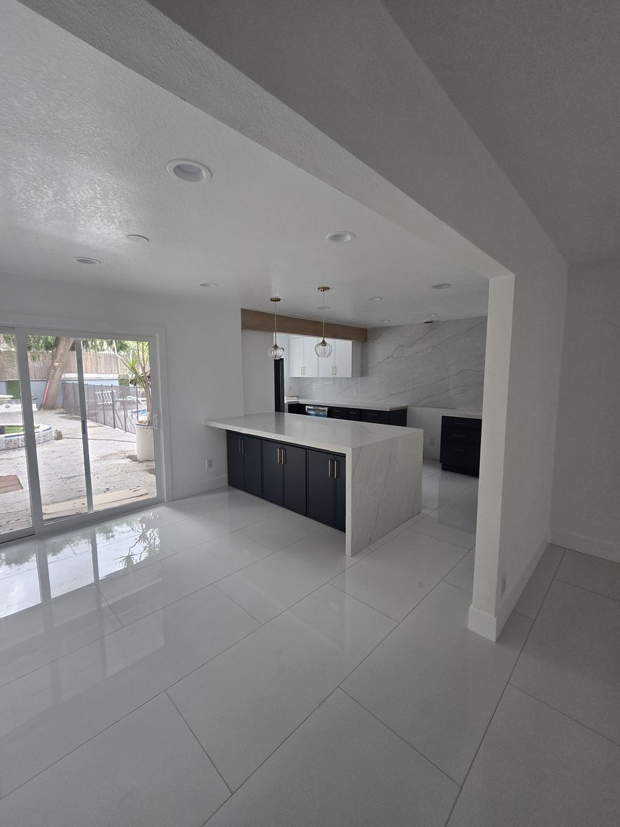 Finished open kitchen in a Norwalk home with navy cabinets, an island and white tile floors