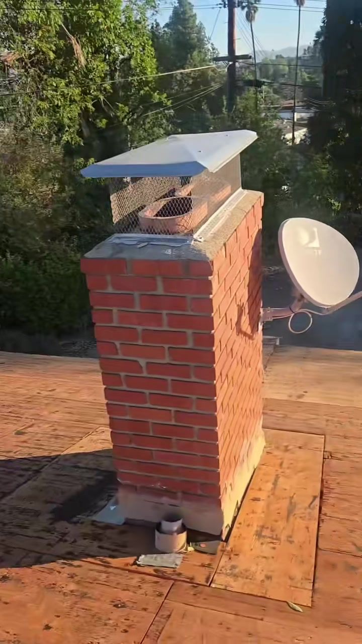 Brick chimney on the stripped roof deck during the tear-off