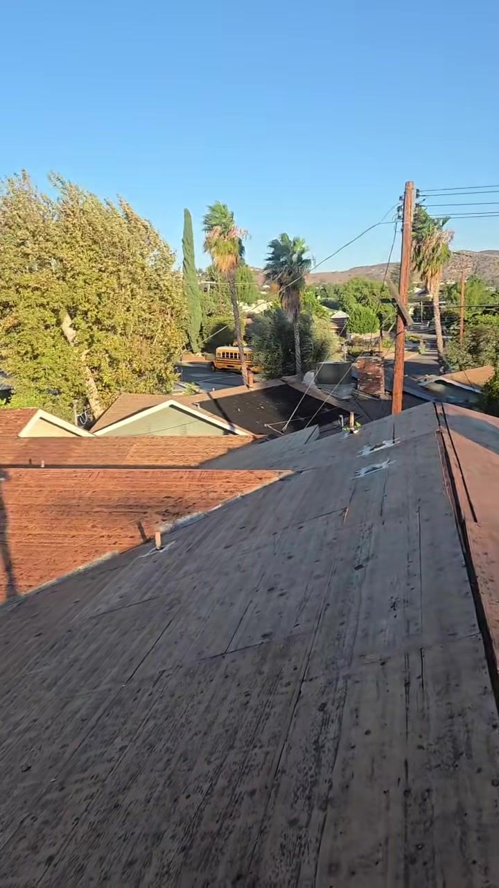 Roof stripped to the plywood deck during the tear-off, with the San Fernando Valley hills behind