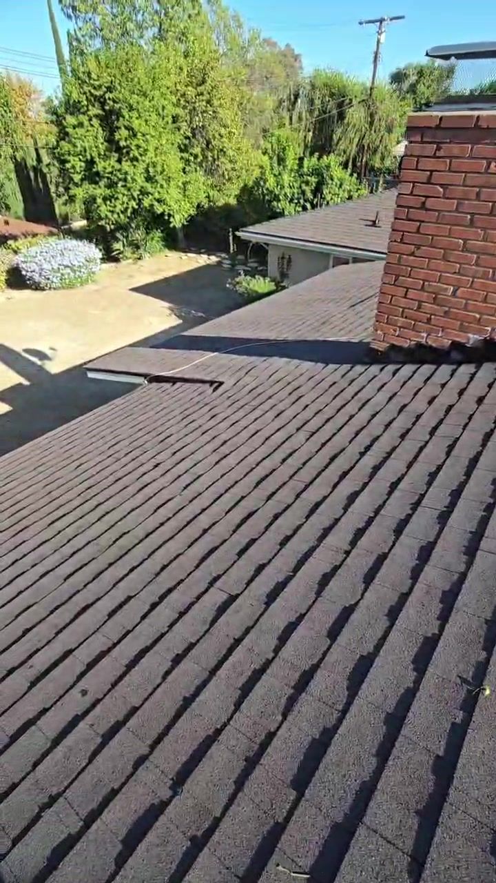 New dark shingles installed around a brick chimney on the Woodland Hills roof