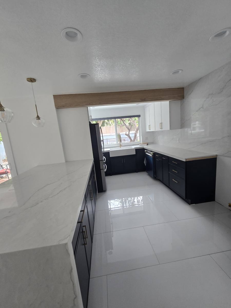 Remodeled kitchen with navy cabinets and white stone counters