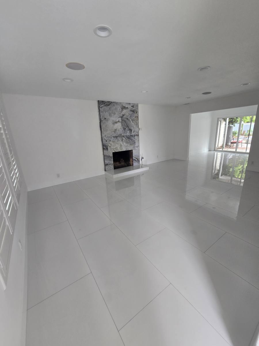 Living room after a whole-home remodel with a marble fireplace surround and large white floor tile